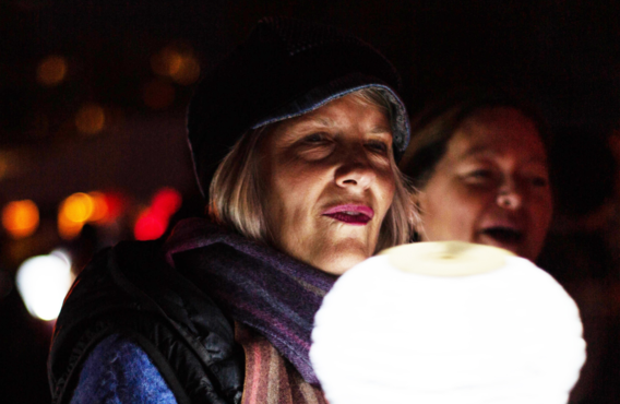 woman holding a white lit lamp at night